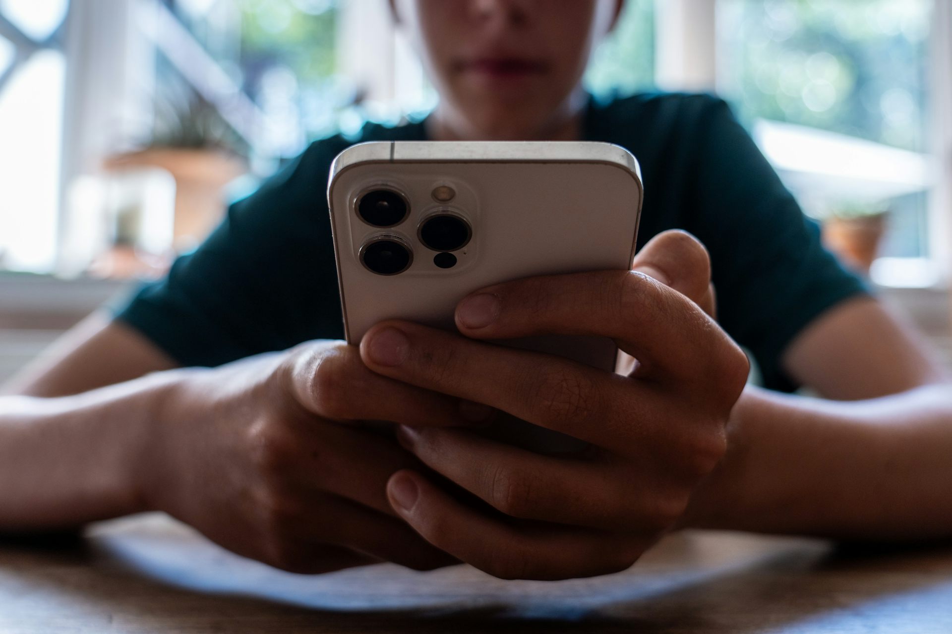 an adolescent boy holds a smartphone